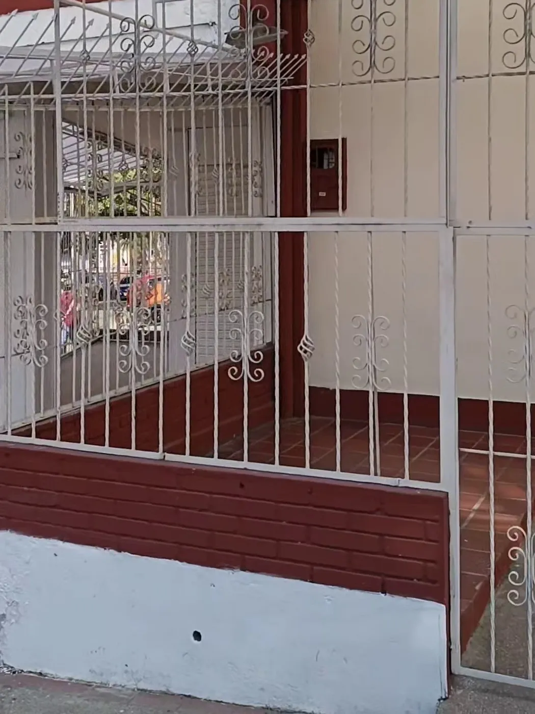 Fachada de la sede del colectivo y Casa de Paso: reja blanca y zócalo color ladrillo